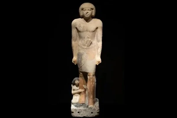 Foto colorida de escultura egípcia feita de calcário em tela preta - Metrópoles