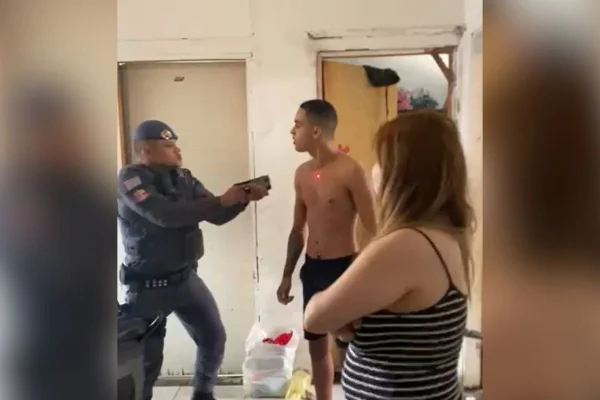Imagem colorida mostra PM apontando arma de choque para homem em casa no bairro do Ipiranga, em São Paulo - Metrópoles