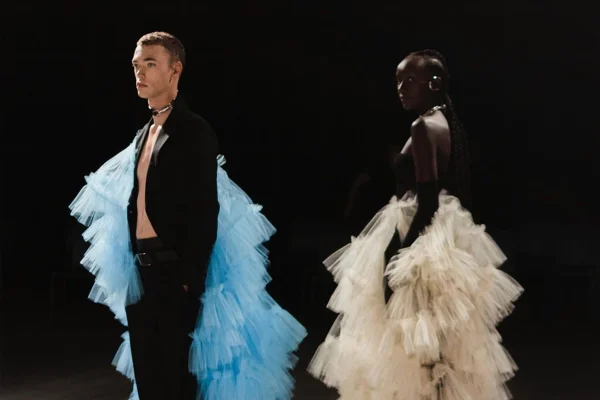 Modelo homem branco e modelo mulher negra usam looks com tule e alfaiataria