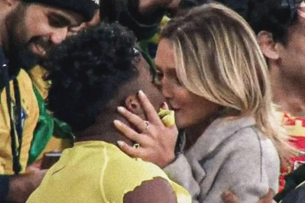 Imagem colorida mostra duas pessoas se beijando em meio a jogo - Metrópoles