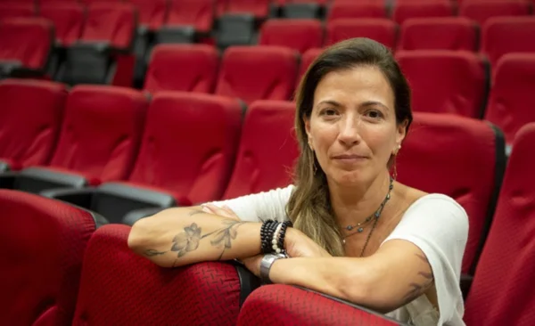 Fotografia colorida mostrando mulher sentada em auditório vazio-Metrópoles