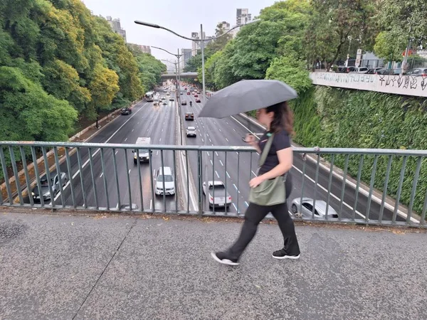 Imagem mostra mulher caminhando com guarda-chuva - Metrópoles