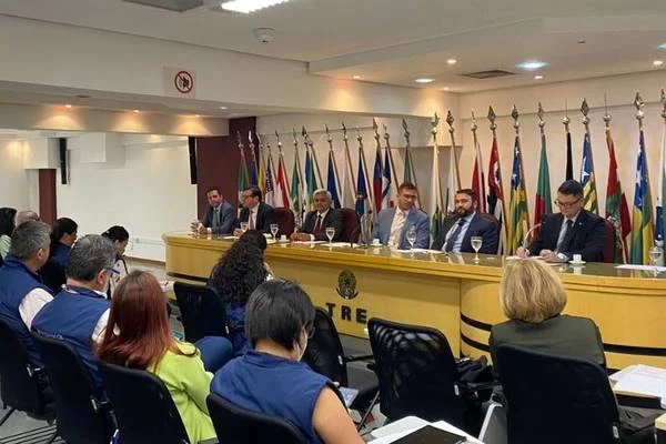 Fotografia colorida de grupo de pessoas acompanhando grupo que discursa