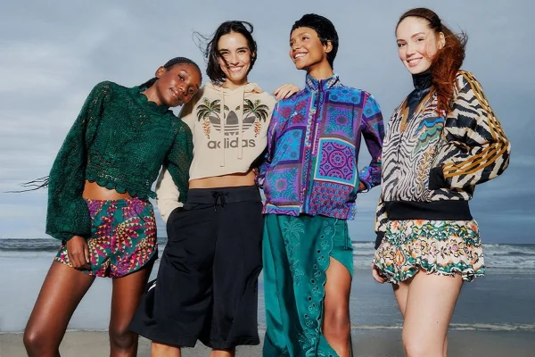 A imagem mostra quatro mulheres vestindo looks coloridos em frente à um mar