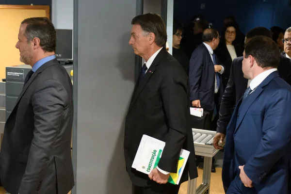 Imagem colorida de Jair Bolsonaro com uma constituição - Metrópoles