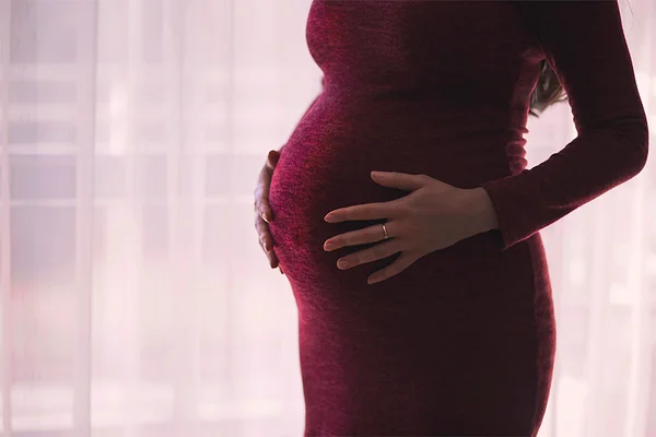 grávida com as mãos apoiadas na barriga