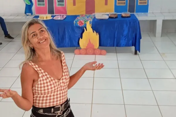 Foto colorida de uma mulher erguendo as mãos aos céus- Metrópoles.