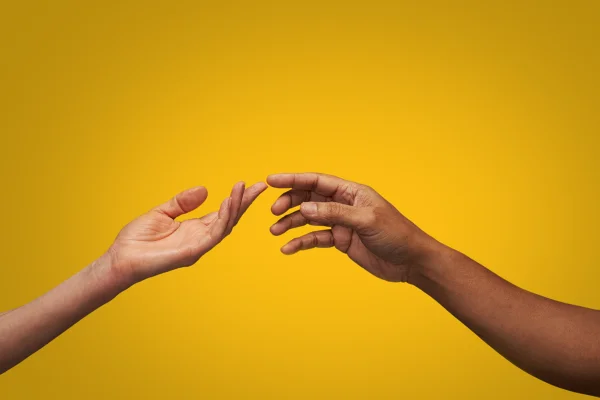 Imagem colorida mostra duas pessoas negras aproximando as mãos um da outra - Metrópoles