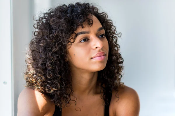 Foto colorida de mulher com cabelo cacheado no corte long bob - Metrópoles