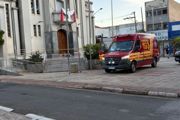 Foto colorida de viatura do Corpo de Bombeiros, próximo à entrada da Igreja Matriz de São Roque, interior de São Paulo. Ao fundo, corpo de atirador esportivo na frente da porta de entrada.