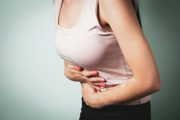 Imagem colorida mostra mulher com dor na barriga e cheia de gases (pum) - Metrópoles