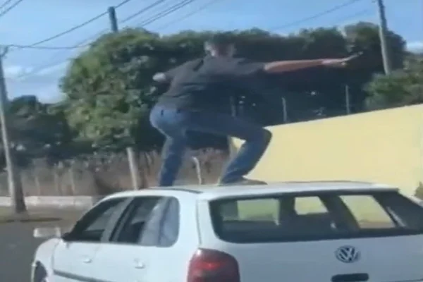 Imagem colorida de um homem em cima do terro do carro durante trânsito em MG - Metrópoles