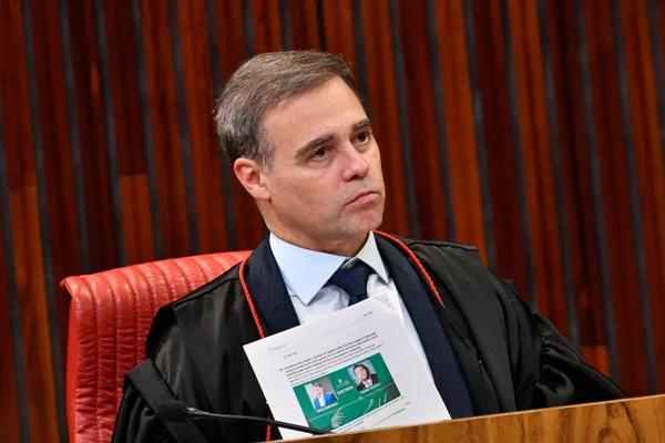 O vice-presidente do Tribunal Superior Eleitoral (TSE), André Mendonça, segura documento contendo imagens do senador Flávio Bolsonaro (PL) e do empresário Daniel Vorcaro