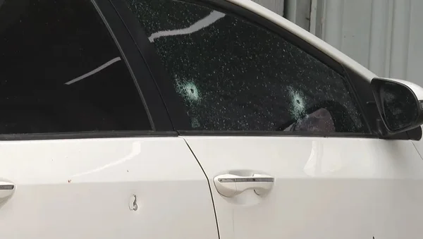 Foto colorida de um carro branco com buracos de bala - metrópoles