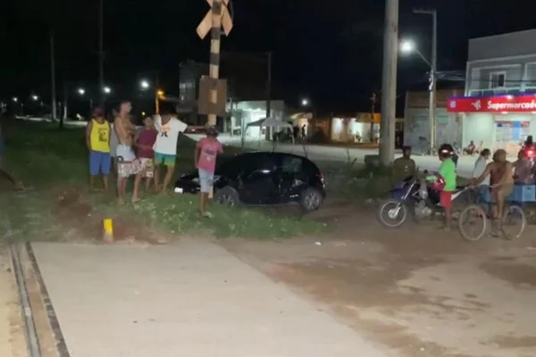 Carro destruído por trem; pessoa em volta do veículo