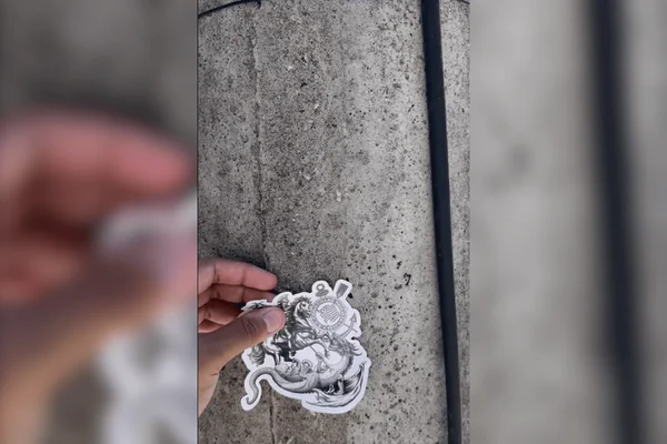 Estagiário do Corinthians colando adesivo em poste no Rio de Janeiro