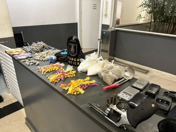 Imagem mostra sacos coloridos e arma apreendidos pela PM em operação no litoral - Metrópoles