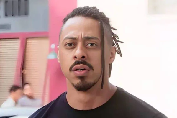 foto colorida de homem negro com tranças presas atrás da cabeça - metrópoles
