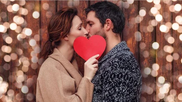 Casal se beijando com coração vermelho na frente