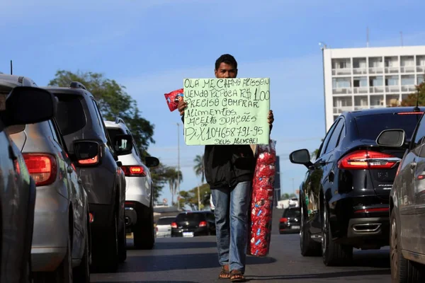 Alisson Lima, 21 anos, espera o semáforo fechar para passar entre os carros balançando um saco de pipoca