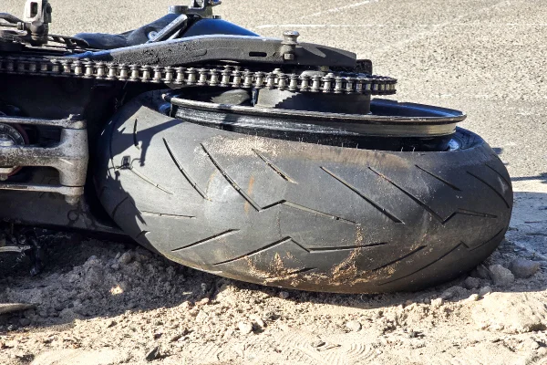 Foto colorida de moto caída na rua após acidente