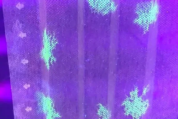 imagem colorida que mostra máscara manchada de verde onde o coronavírus encostou