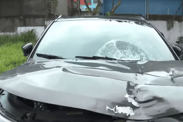 Imagem de um carro preto com o para-brisas e o capô amassados após um acidente de trânsito - Metrópoles