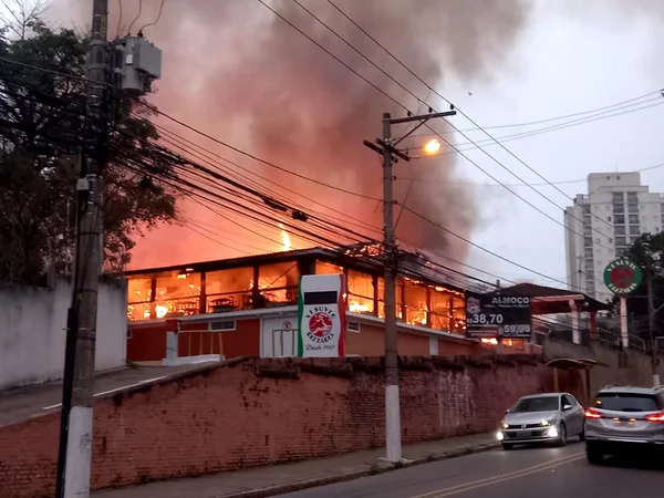 Estrutura de pizzaria com fogo em seu interior, exalando fumaça cinza - Metrópoles