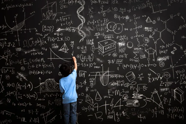 Imagem mostra criança pequena escrevendo equações matemáticas em uma lousa de giz - Metrópoles