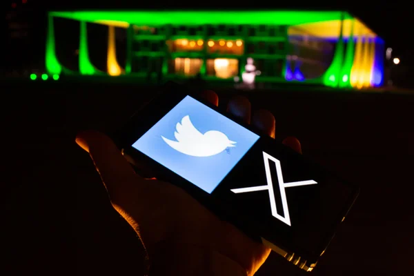 Celular com imagens do site e logo do Twitter em frente ao STF1