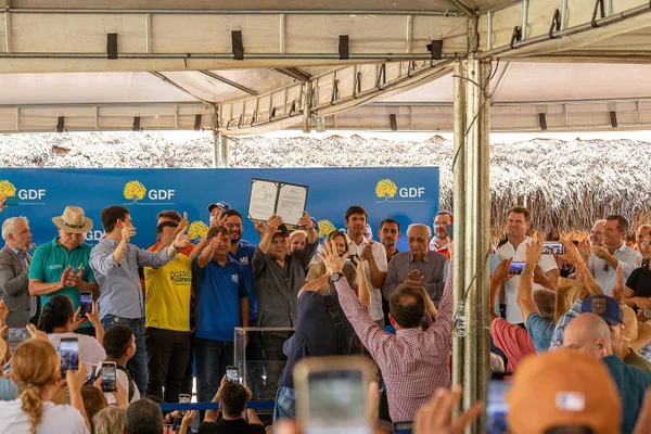 Fotografia colorida mostrando homem segurando pasta com lei sancionada em palco-Metrópoles