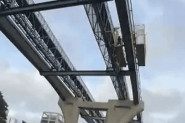 Imagem colorida de um funcionário pendurado por cordas de proteção após cair de uma plataforma de suporte em obra - Metrópoles