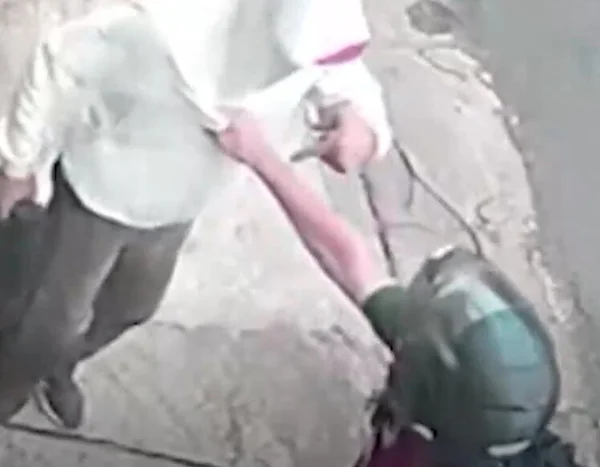 Imagem colorida mostra PM de capacete segurando em colarinho de suspeito