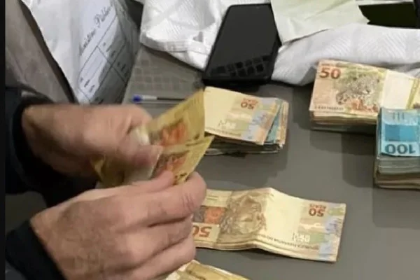 Imagem colorida de mão e notas de 50 e 100 reais