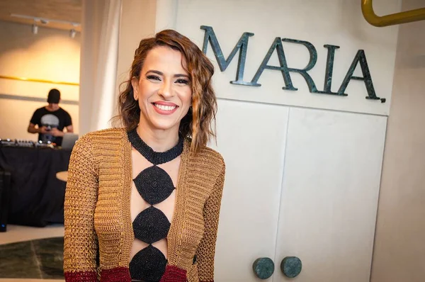 Mulher sorridente em frente a letreiro
