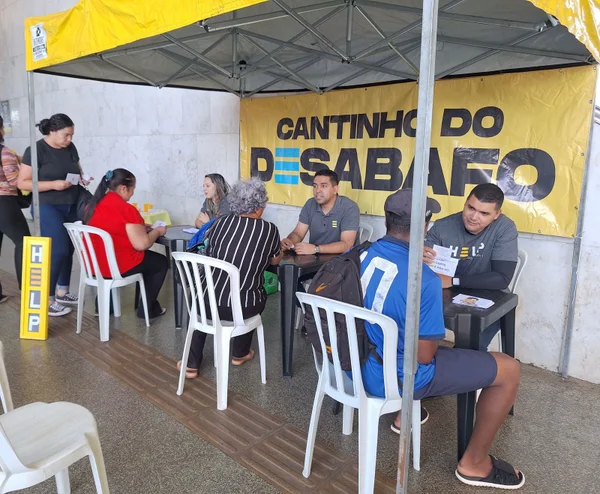 Pessoas conversando sentadas em cadeiras em baixo de uma tenda
