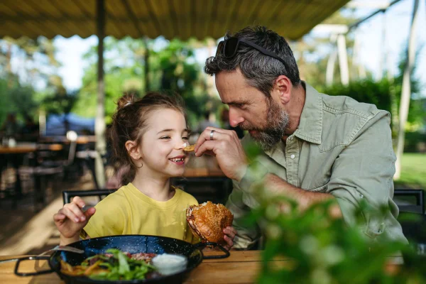 foto colorida de pai e filha celebrando o dia dos pais em restaurante
