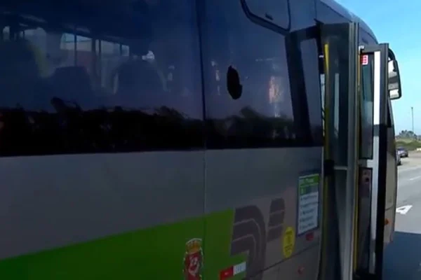 ônibus com adesivo verde na lateral com vidro quebrado por pedra - Metrópoles