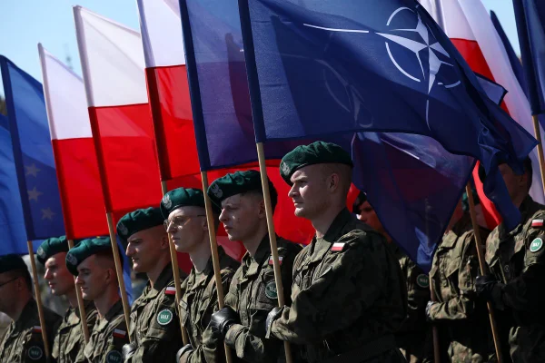 Imagem colorida mostra soldados da Polônia segurando bandeiras da Otan - Metrópoles