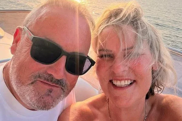 Foto colorida de mulher ao lado de homem em ambiente aberto com lago no fundo junto ao pôr do sol - Metrópoles.