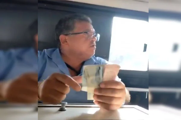 Homem de óculos e camisa azul com dinheiro na mão