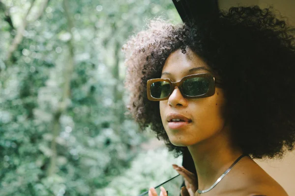 Modelo negra de óculos escuros em um jardim