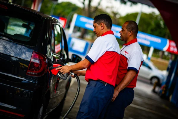 Foto colorida de homens abastecendo carro