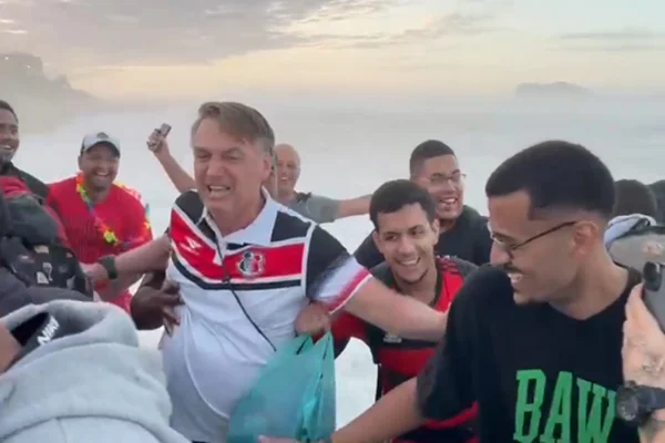 Imagem colorida de Jair Bolsonaro no momento em que onda o atinge na Barra da Tijuca (RJ)