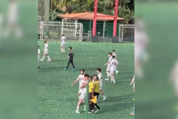 Imagens coloridas mostram jogadores de futebol de time Sub-17, camisas brancas do time do São Paulo, calções e meiões brancos, brigando com árbitro do jogo, de camisa amarela, calções e meios pretos