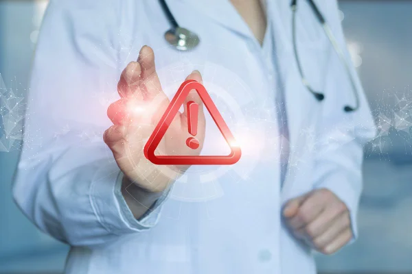 Ilustração colorida com pessoa real, vestida de branco, representando um médico com sinal de exclamação em vermelho em frente - Metrópoles.