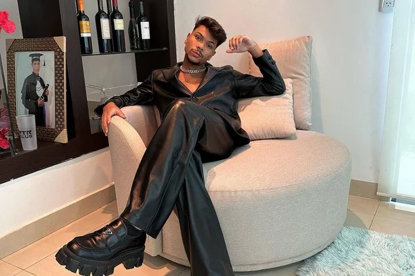 Foto colorida de Jessé Aguiar usando roupa toda preta e sentado em um sofá - Metrópoles