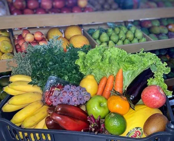 Cesta com frutas e verduras como banana, alface, cenoura, uva, pimentão e outros produtos