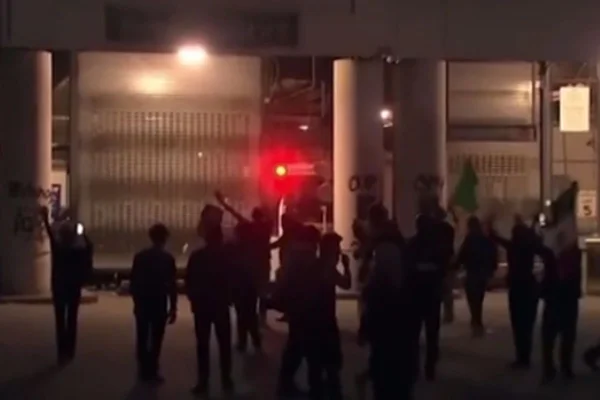 Imagens coloridas mostram pessoas em protesto durante a noite, em Los Angeles, uma luz vermelha à frente