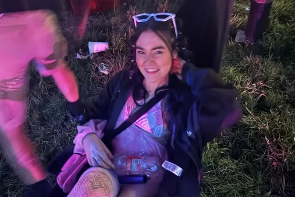 Mulher sorri deitada em grama em festa - Metrópoles